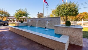 A rectangular pool with multiple waterfalls, surrounded by stone walls and a flagpole. - Best Western Plus Galleria Inn & Suites (Memphis)