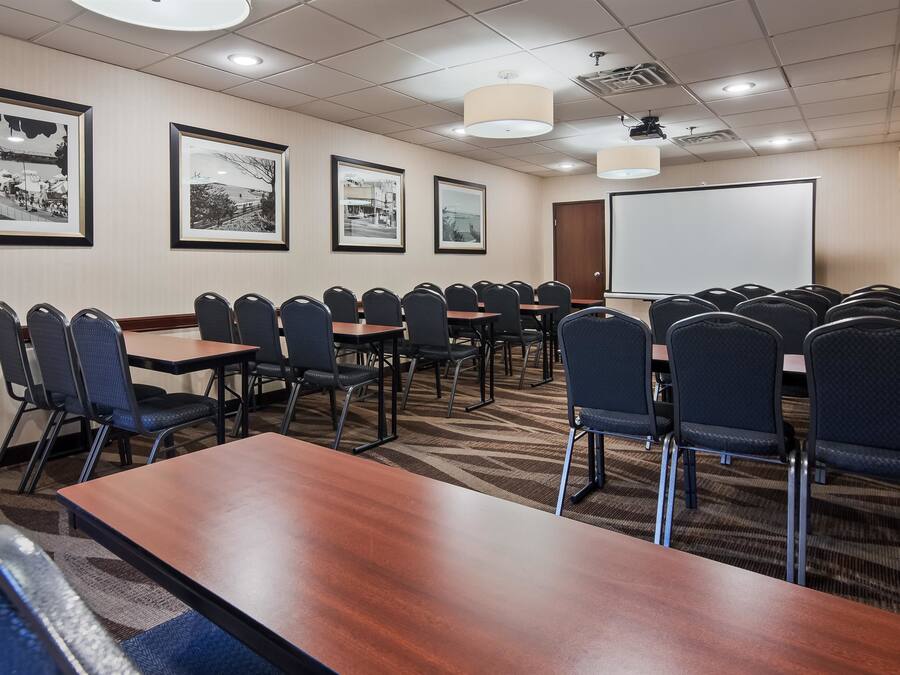 A conference room with multiple tables and chairs, framed pictures on the walls, and a whiteboard.