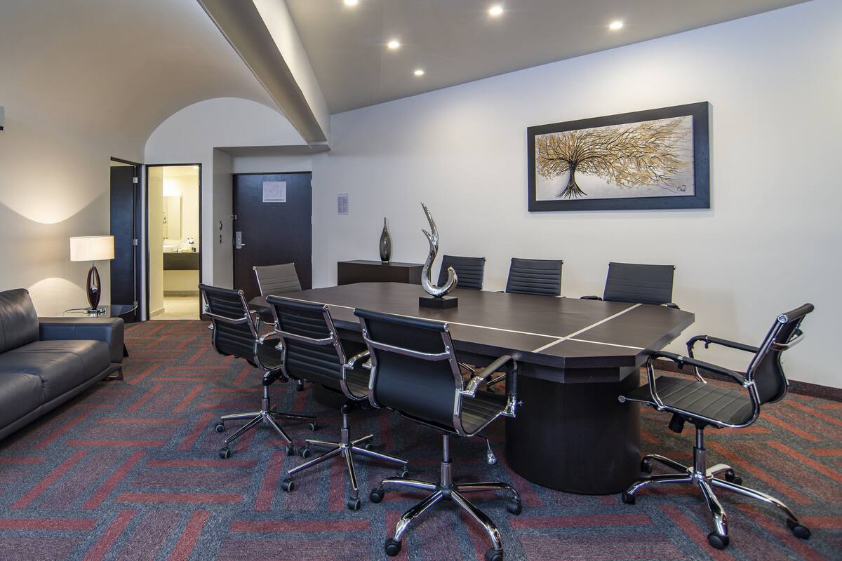 A conference room with a long table, six chairs, a sofa, and a lamp.