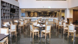A spacious restaurant with multiple tables and chairs, a bar area, and a cactus wall decoration. - Holiday Inn Mexico Dali Airport by IHG (Mexico City)