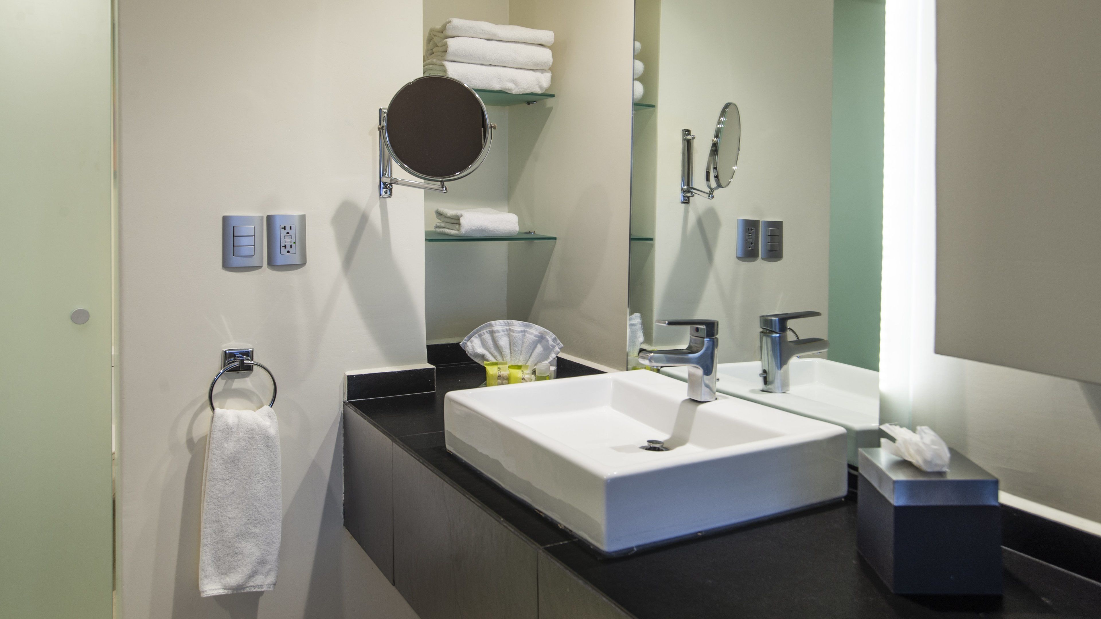 A modern bathroom with a large sink, a mirror, and a towel rack.