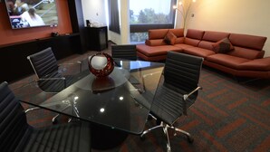 A conference room with a glass table, black chairs, a red sofa, and a TV on the wall. - Holiday Inn Mexico Dali Airport by IHG (Mexico City)