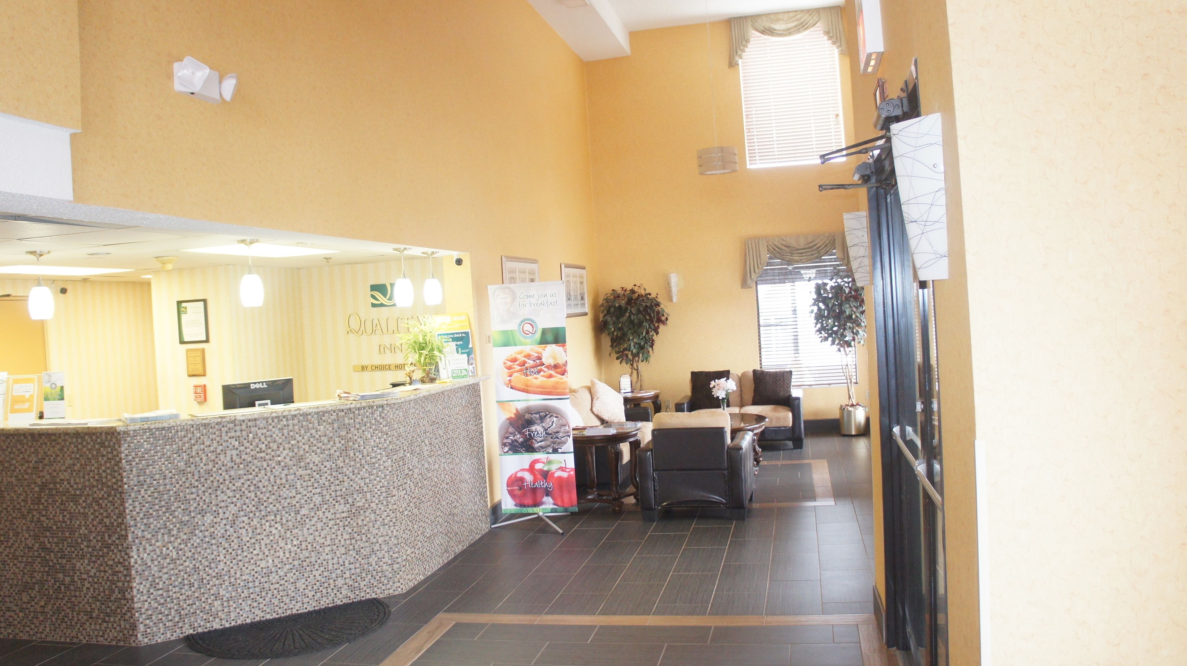 A reception area with a counter, a desk, and a seating area with a plant.