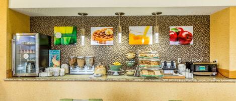 A breakfast bar with a refrigerator, coffee machine, and various food items.
