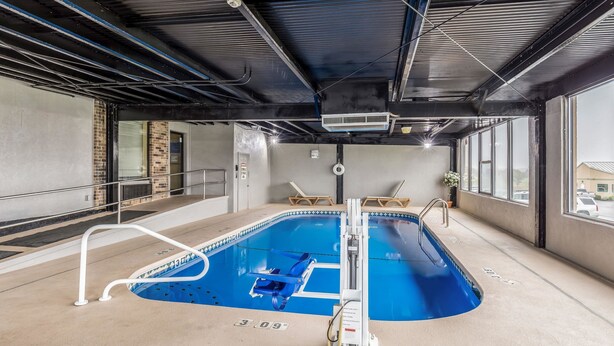 An indoor swimming pool with a diving board, a lifeguard chair, and a pool ladder. - Quality Inn Rolla (Rolla)