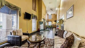 A hotel lobby with leather sofas, a glass coffee table, and a view of the dining area. - Quality Inn Rolla (Rolla)