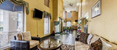 A hotel lobby with leather sofas, a glass coffee table, and a view of the dining area.
