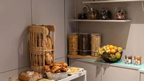 Un área de cocina con pan, pasteles y frascos de conservas en estantes.