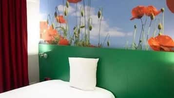 A hotel room with a bed, green walls, a red curtain, and a mural of red flowers on the wall.