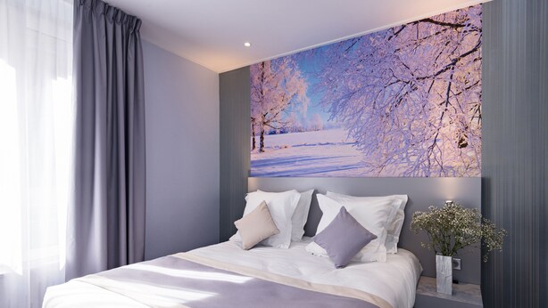 A modern bedroom with a large bed, a nightstand with a vase, and a wall-mounted painting of a winter landscape. - Hotel Les Jardins de Montmartre (Paris)