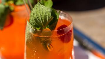 Un vaso de bebida de naranja con hojas de menta, posiblemente un cóctel, sobre una mesa.