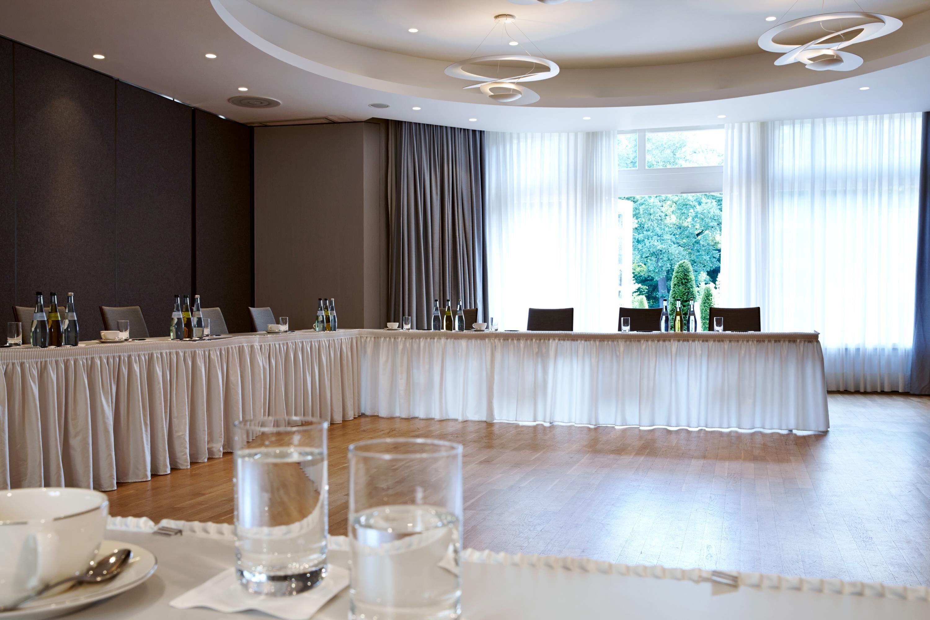 Un salón de conferencias con una larga mesa, sillas y vasos de agua.