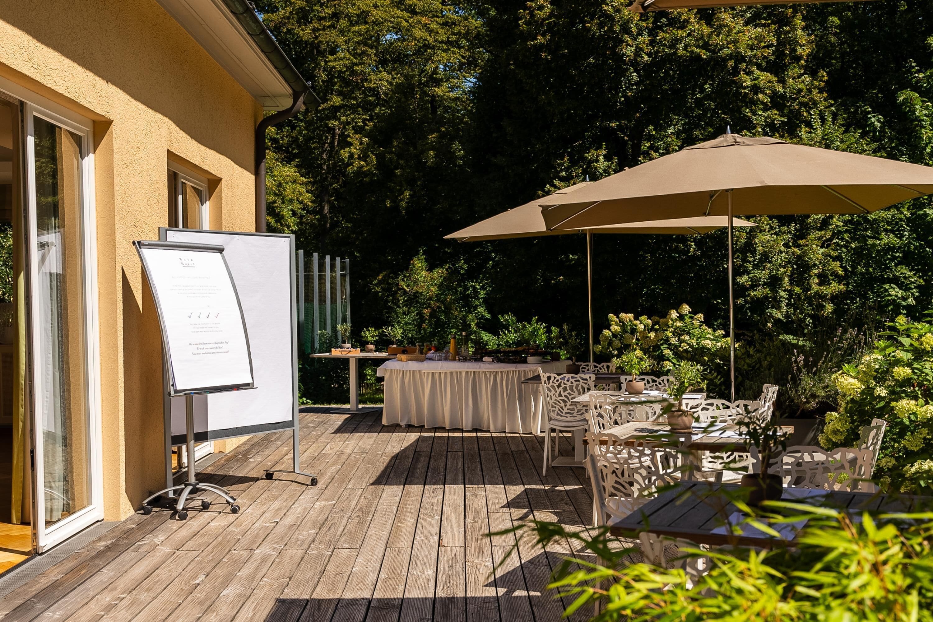 Eine Außenpatio mit einer Tafel, einem Tisch und Stühlen sowie einem Sonnenschirm.