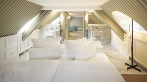 A modern hotel room with a large bed, a bathroom with a marble sink, and a view of the city through the window.