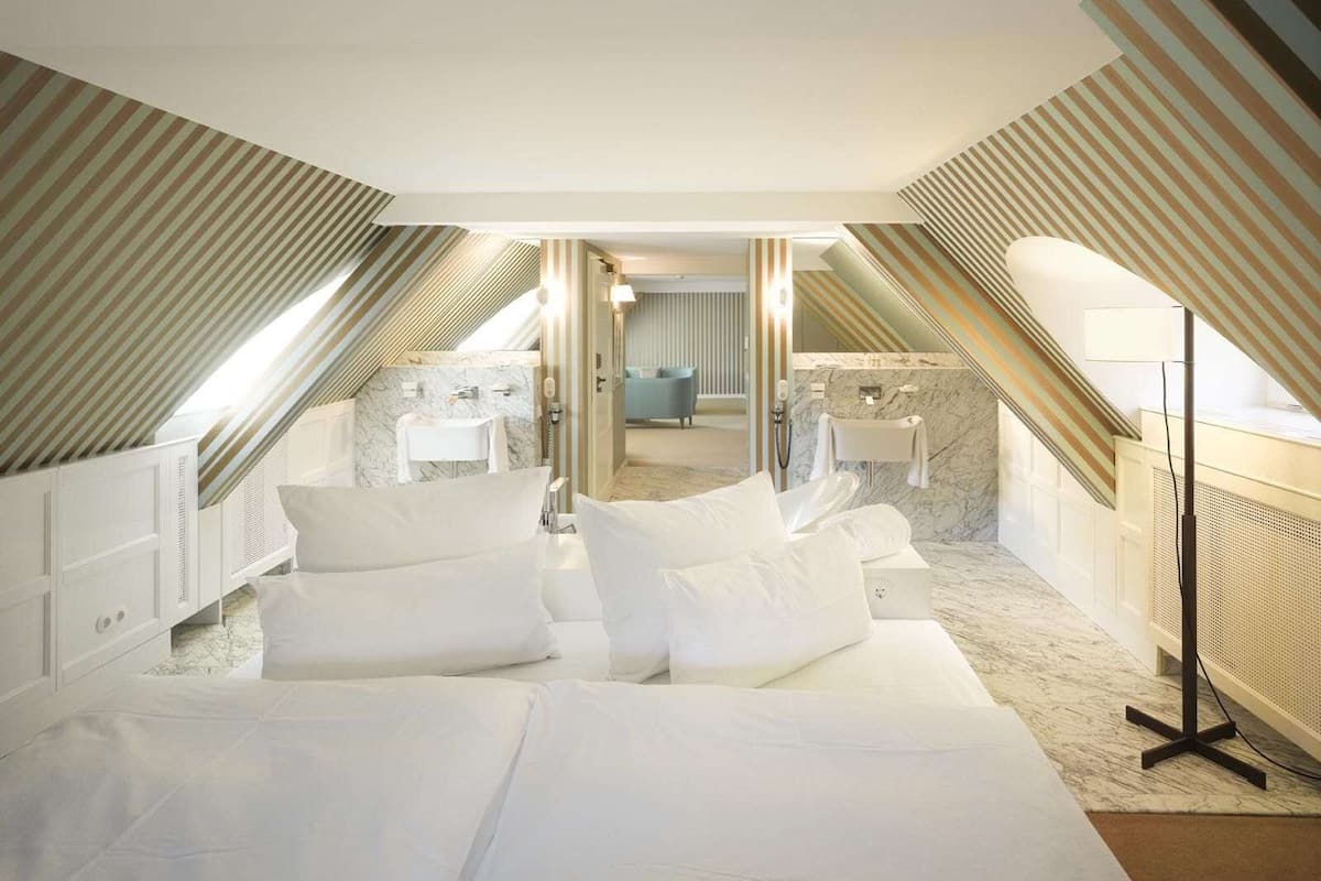 A modern hotel room with a large bed, a bathroom with a marble sink, and a view of the city through the window.