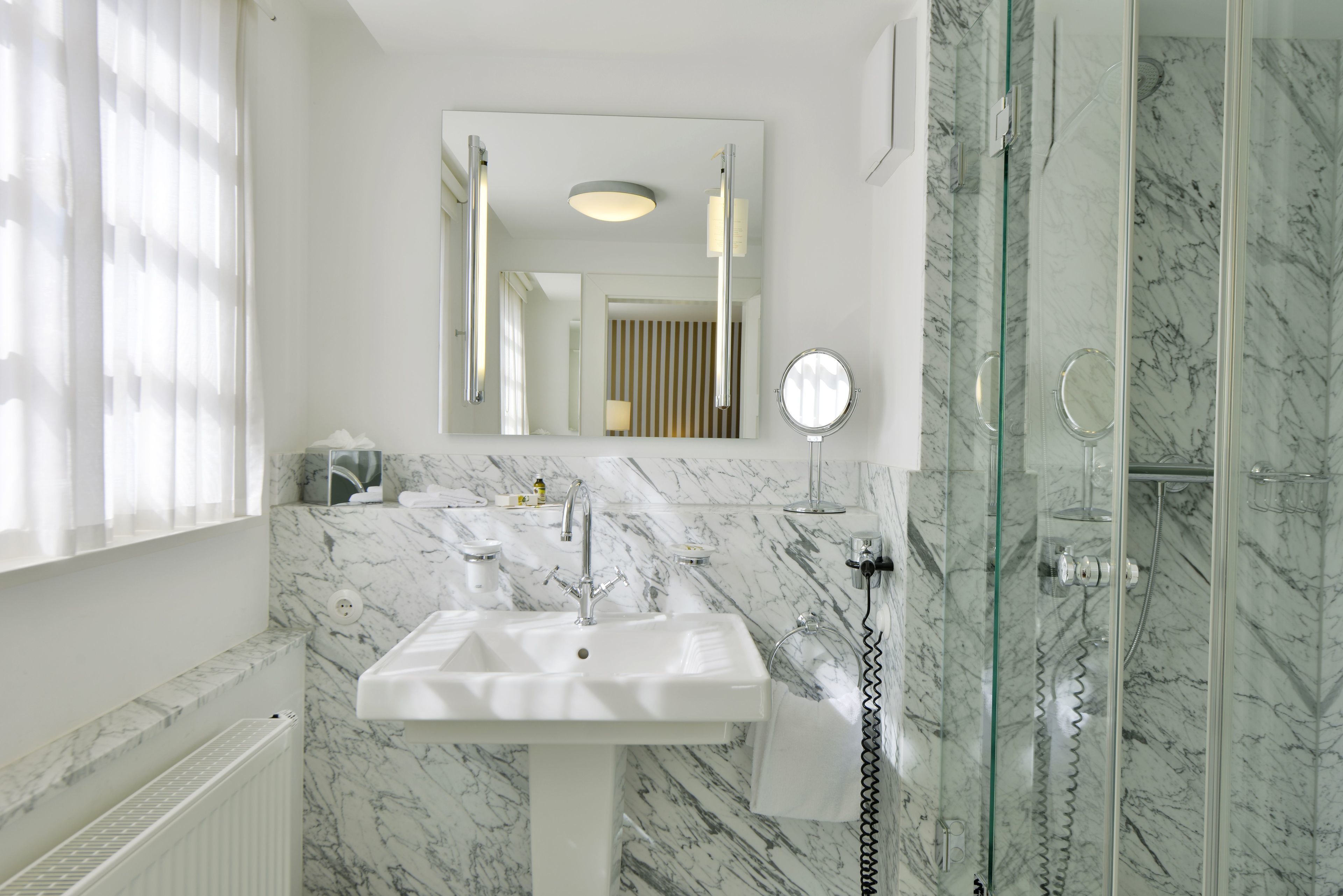 A bathroom with a white sink, a mirror, and a glass-enclosed shower.
