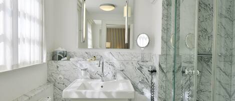 A bathroom with a white sink, a mirror, and a glass-enclosed shower.