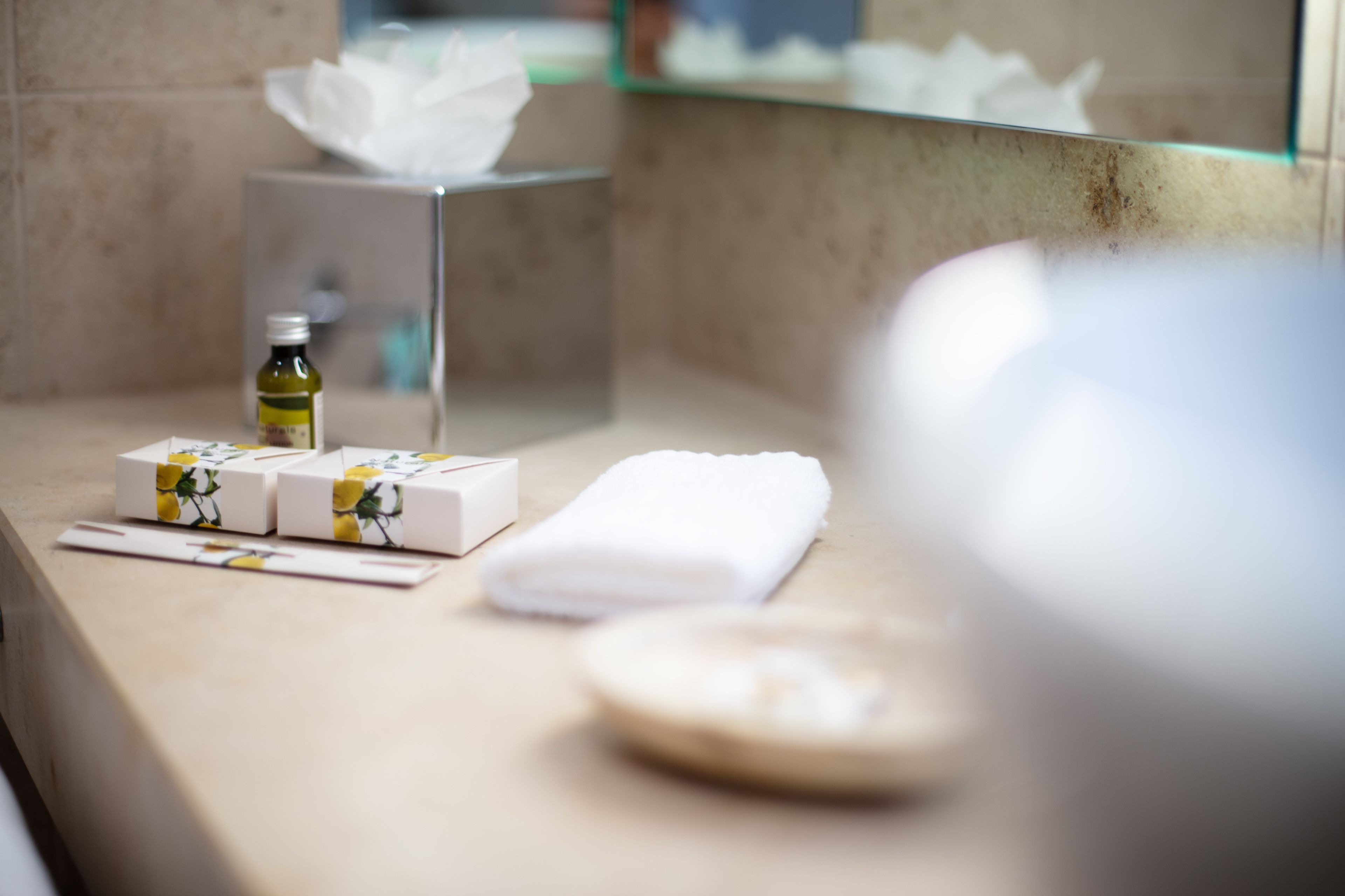 A bathroom counter with a tissue box, a bottle of lotion, and a folded towel.