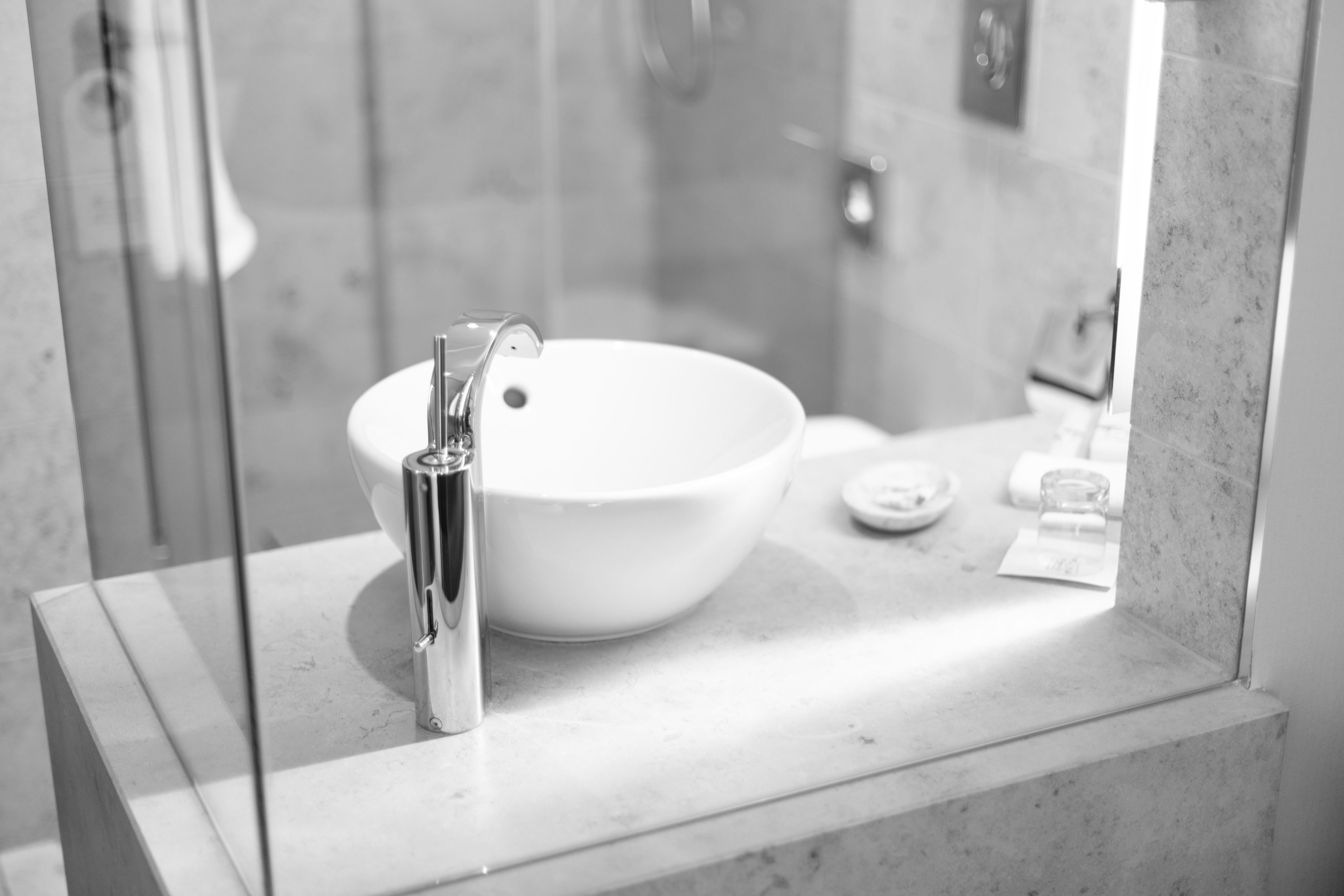Un baño con un lavamanos blanco, grifo cromado y cabina de ducha de vidrio.