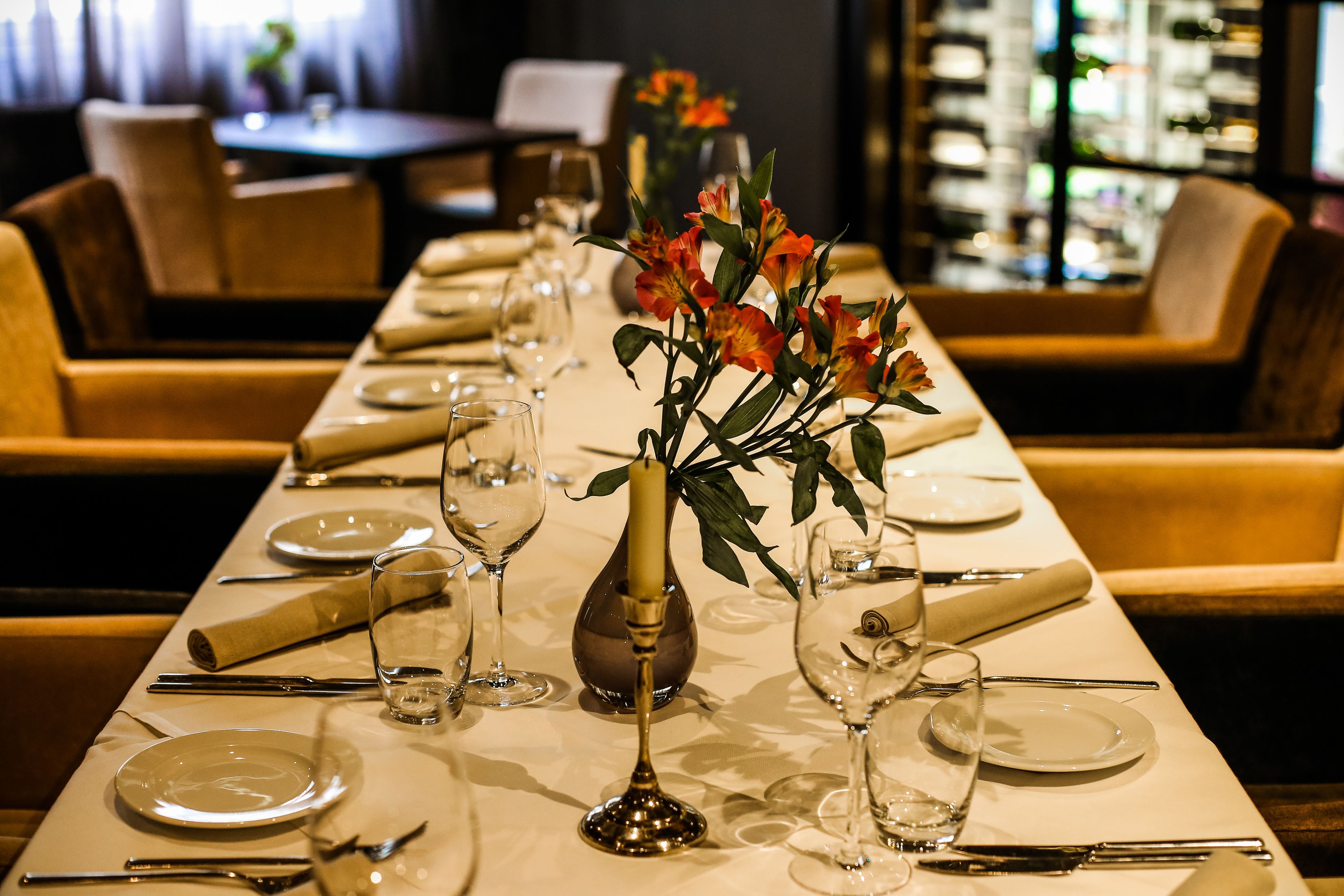 Una mesa de comedor dispuesta con platos, cubiertos y un florero.