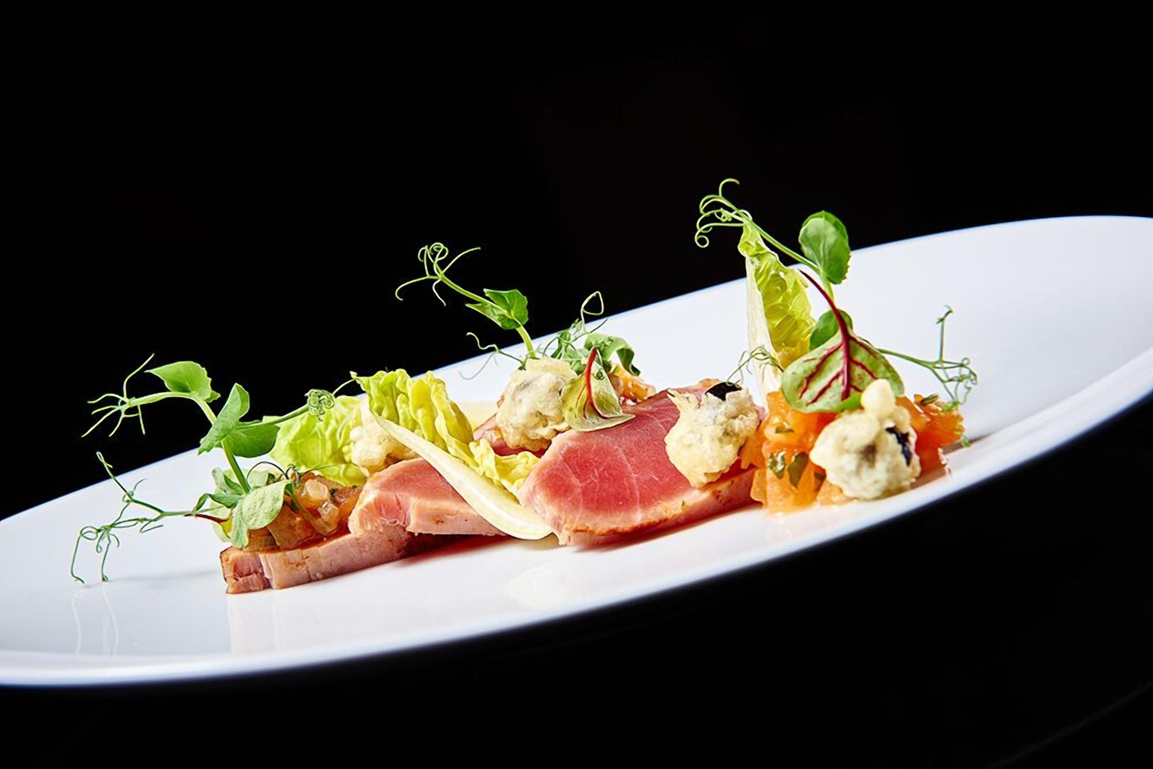 Un plato blanco con una variedad de alimentos, incluyendo carne, verduras y guarniciones.