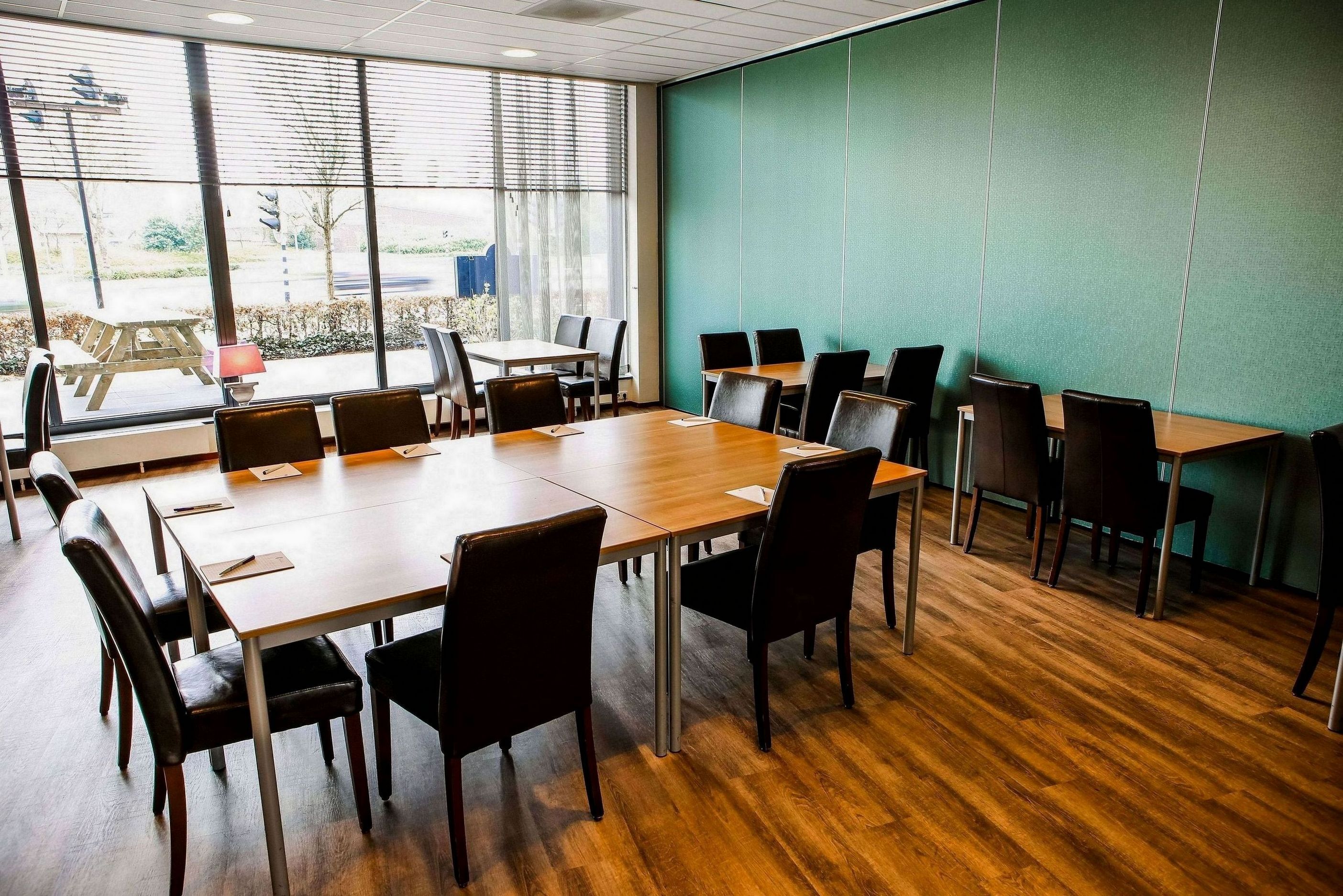 Une salle de conférence dotée d’une grande table, de nombreuses chaises et offrant une vue sur l’extérieur grâce à de grandes fenêtres.