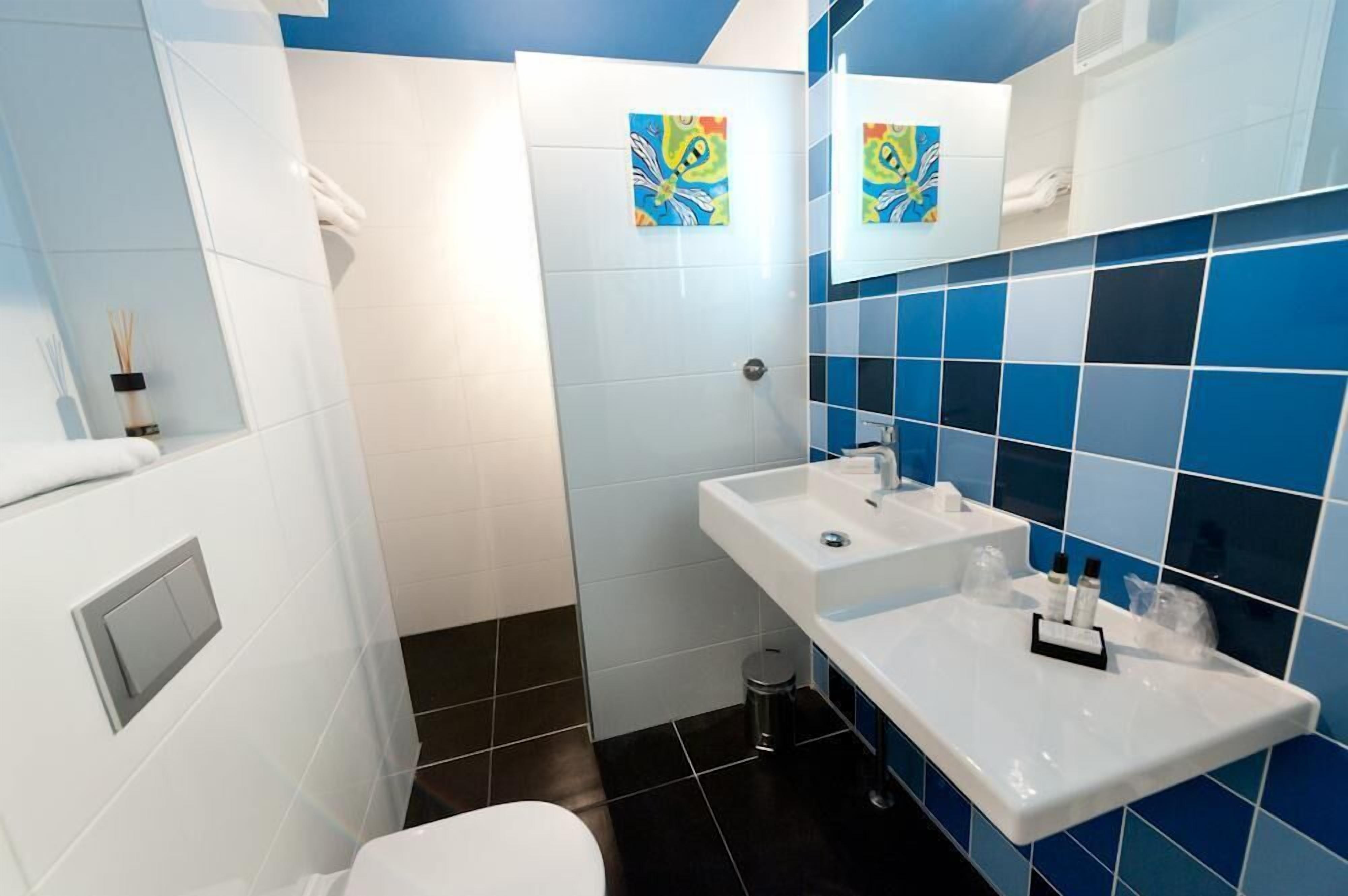Un baño con lavamanos blanco, espejo y azulejos azules.