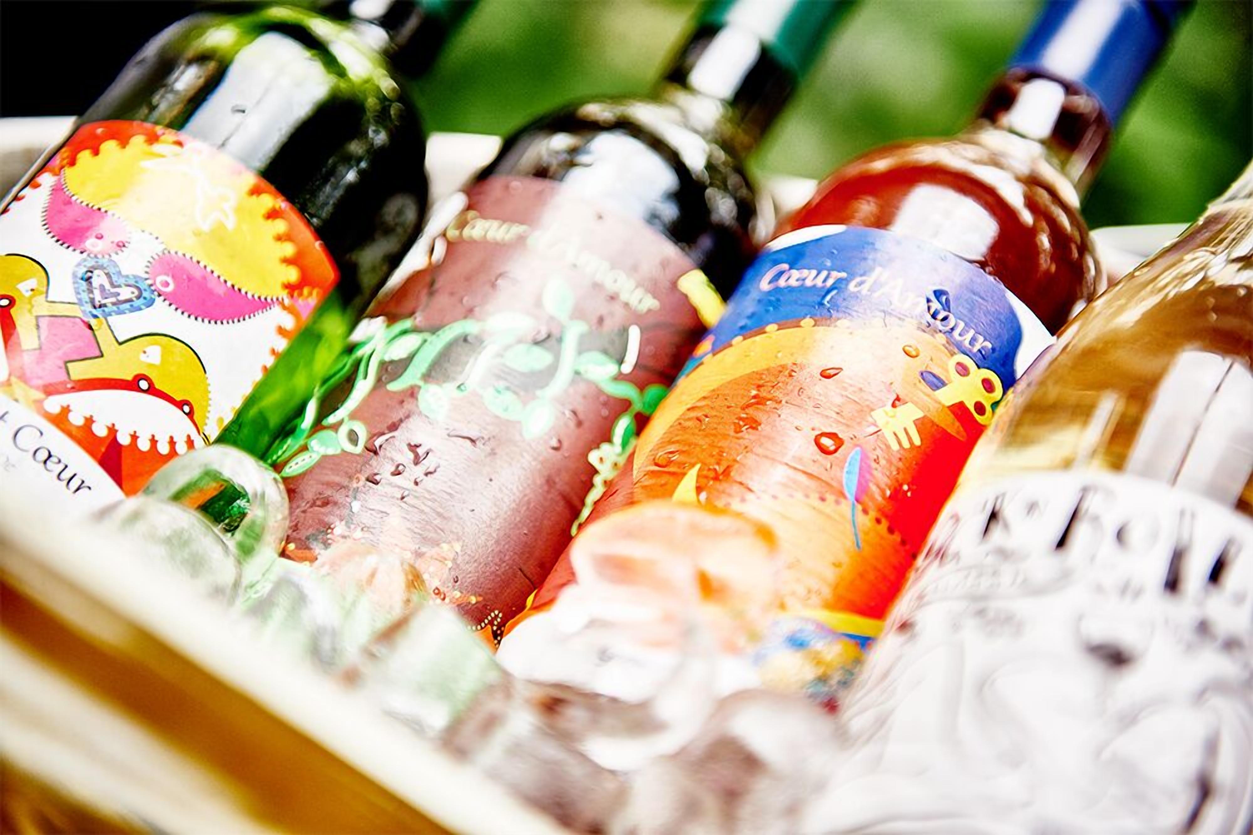 Una selezione di bottiglie di vino con etichette colorate in un contenitore di vetro.
