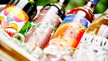 Una selezione di bottiglie di vino con etichette colorate in un contenitore di vetro.