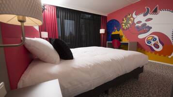 Una habitación de hotel con una cama, una lámpara, una cortina y un mural colorido en la pared.