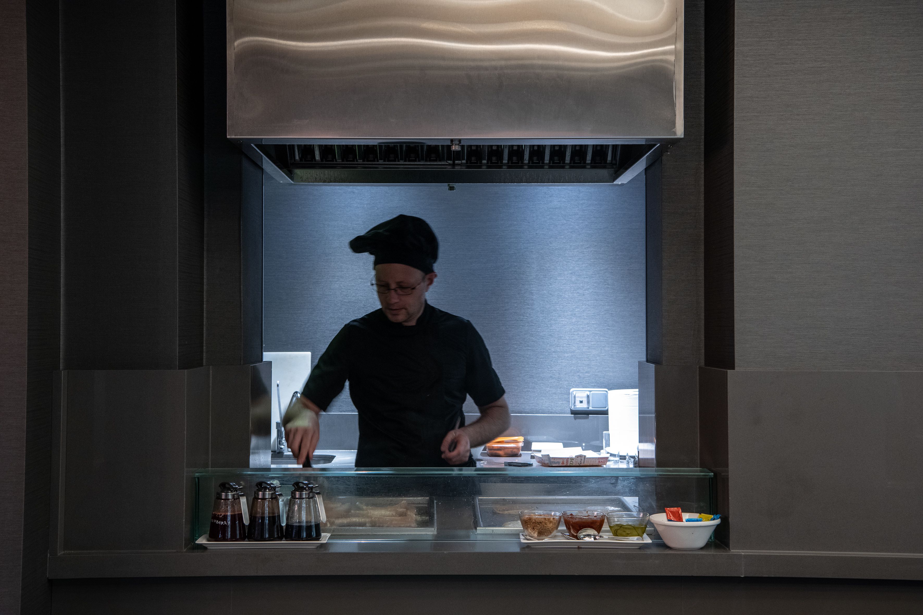 Uno chef in cucina professionale con elettrodomestici in acciaio inossidabile e un design moderno.