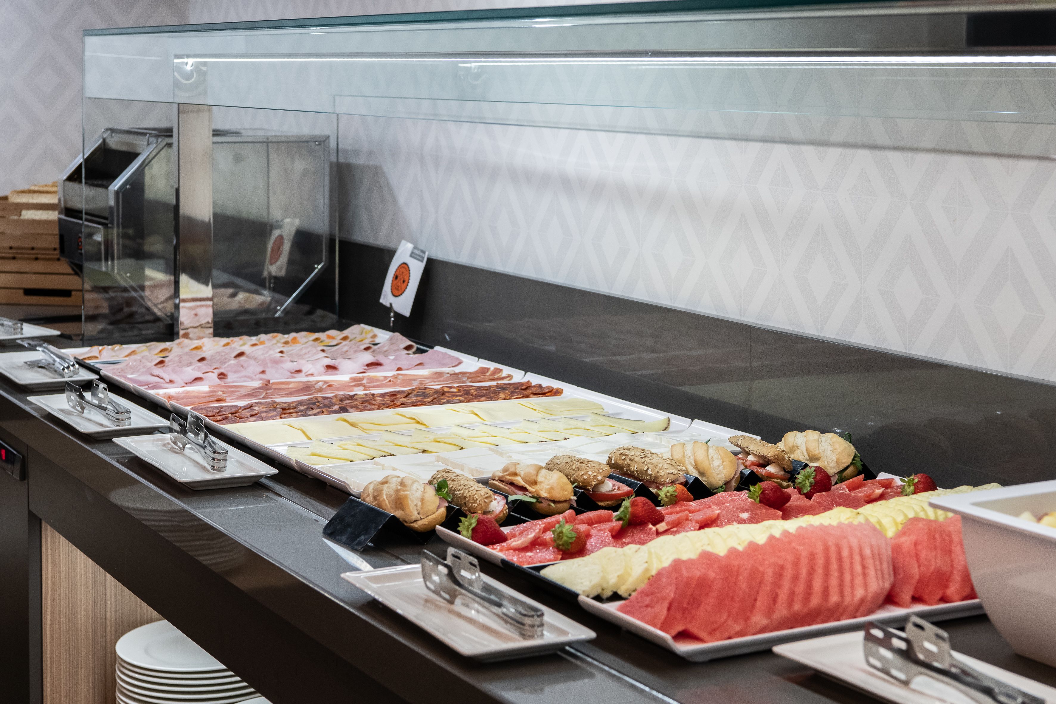 Un buffet proposant une variété de plats, notamment des viandes, des fromages et des fruits.