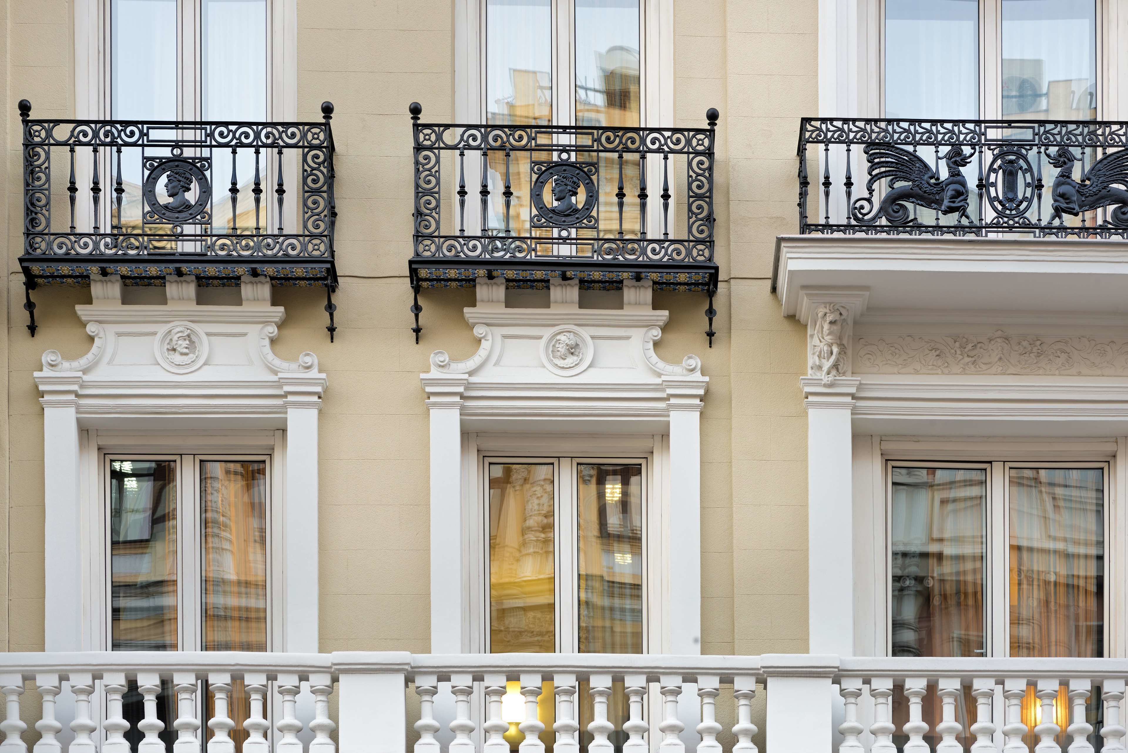 Egy épület homlokzata, melyen három-három balkon található, mindegyik gazdagon díszített, fekete színű, kovácsoltvas korláttal és fehér mellvéddel.