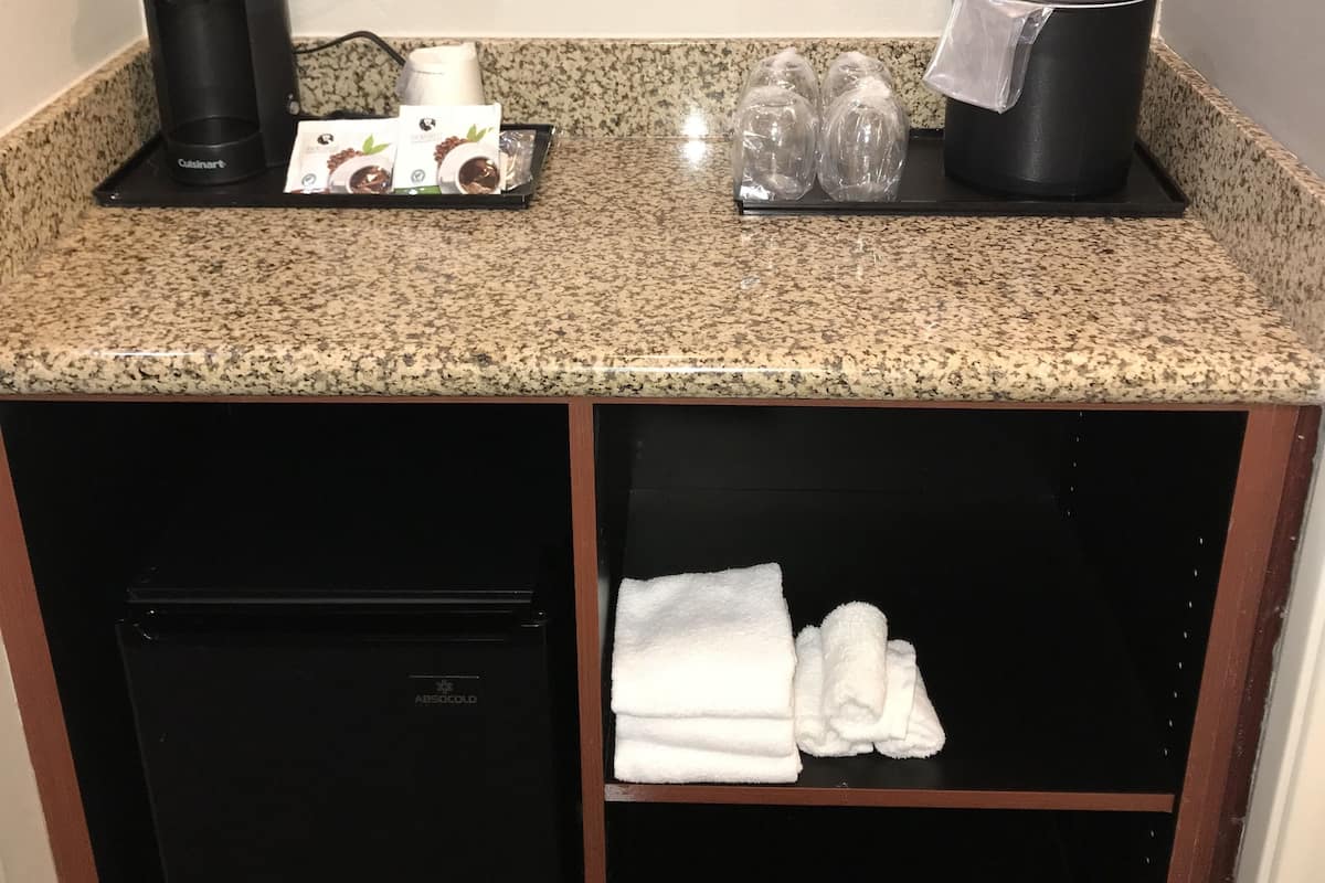 A kitchenette with a coffee maker, tea kettle, and glassware on the countertop.