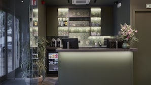 A reception area with a counter, a potted plant, and a decorative wall with shelves. - Urban Yard (Brussels)