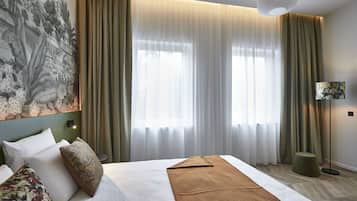 Una habitación de hotel con una cama grande, un otomano verde, una lámpara de pie y un cuadro en la pared.