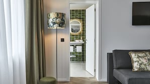 A modern living room with a sofa, a lamp, and a view into a bathroom with green tiles. - Urban Yard (Brussels)