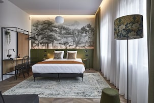Un dormitorio moderno con una cama grande, un escritorio con una silla, una lámpara de pie y un mural en la pared.