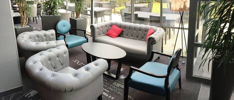 A modern indoor seating area with a grey sofa, two armchairs, and a small table.