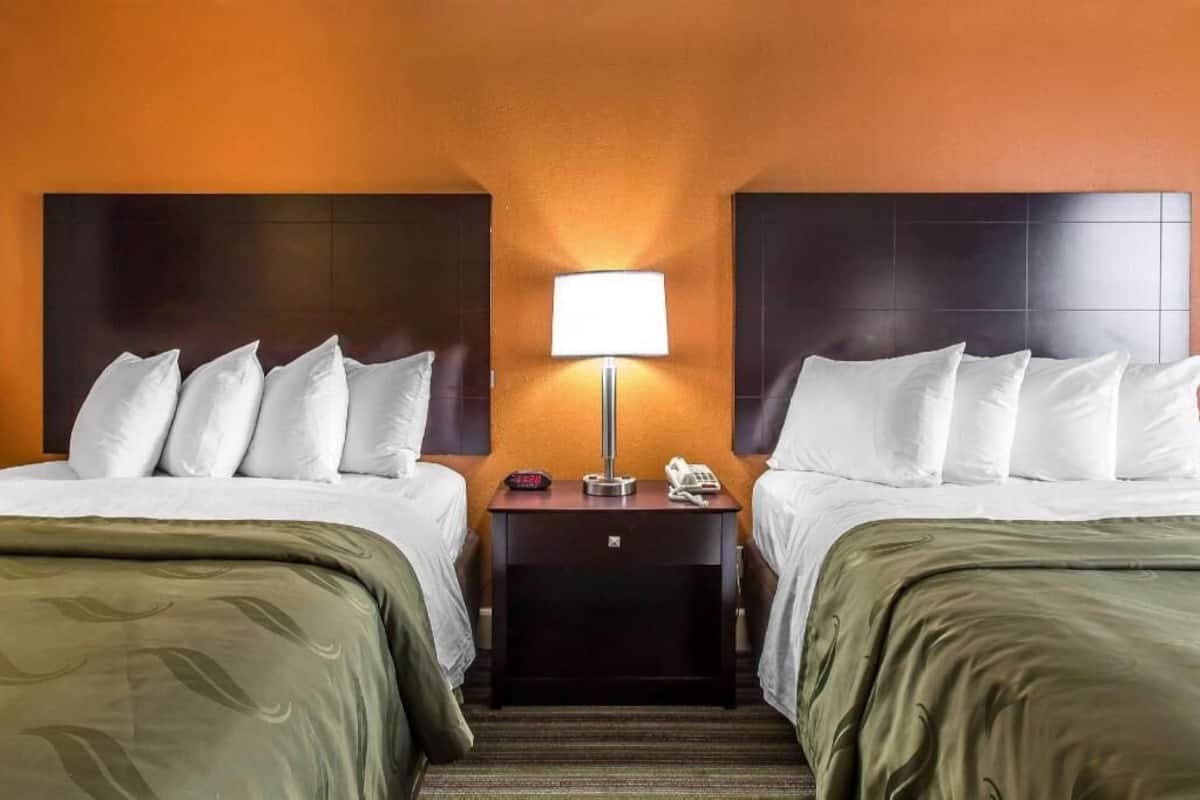 Une chambre d’hôtel avec deux lits, une table de chevet, une lampe et un téléphone.