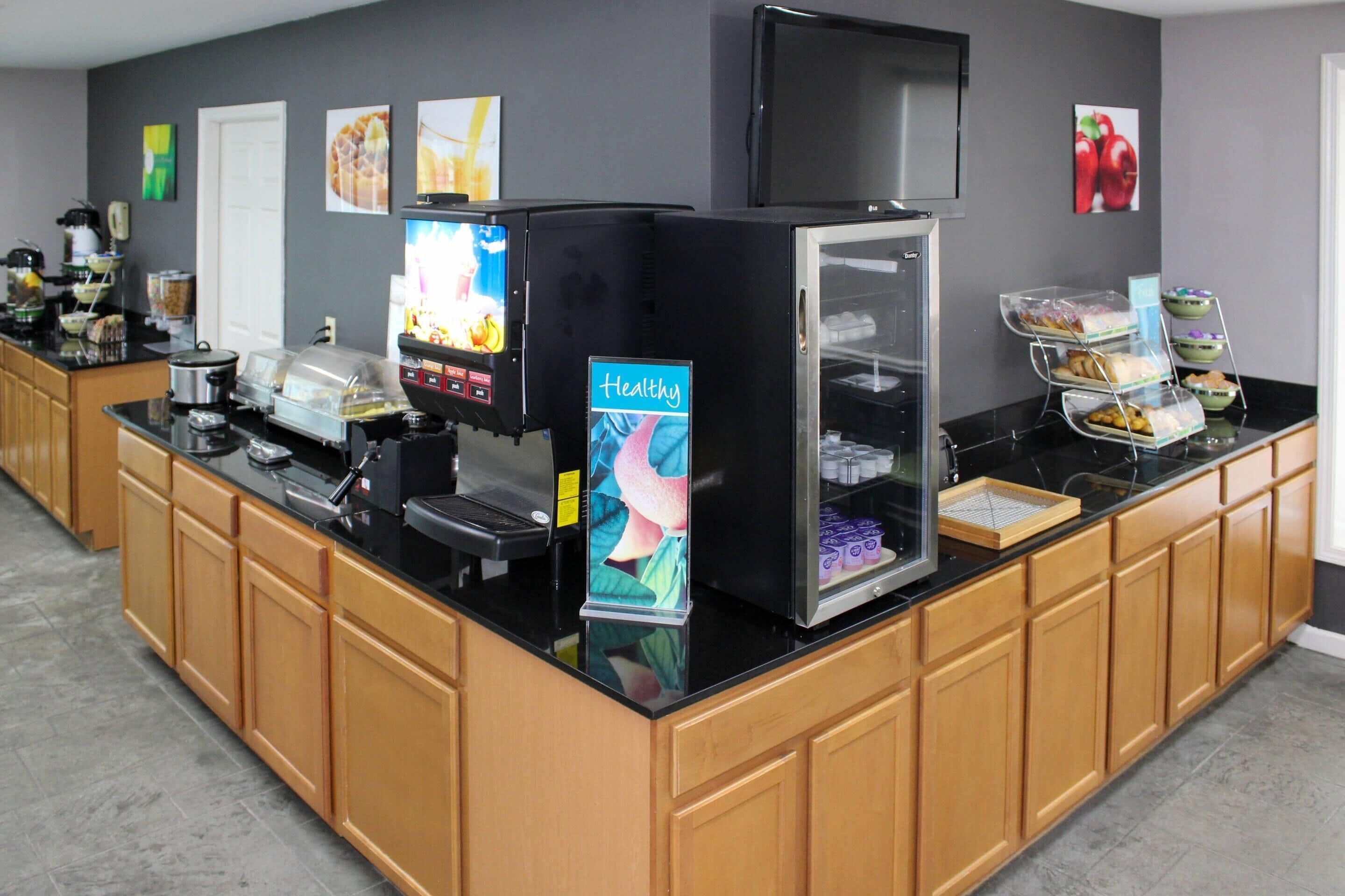 A self-service breakfast bar with a coffee machine, a refrigerator, and a display case.