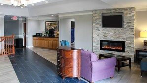 A modern living room with a stone fireplace, a flat-screen TV, and a wooden cabinet. - Quality Inn Crossville Near Cumberland Mountain State Park (Crossville)