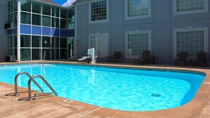 A swimming pool with metal ladders, adjacent to a building with large windows and a tiled roof. - Quality Inn Crossville Near Cumberland Mountain State Park (Crossville)