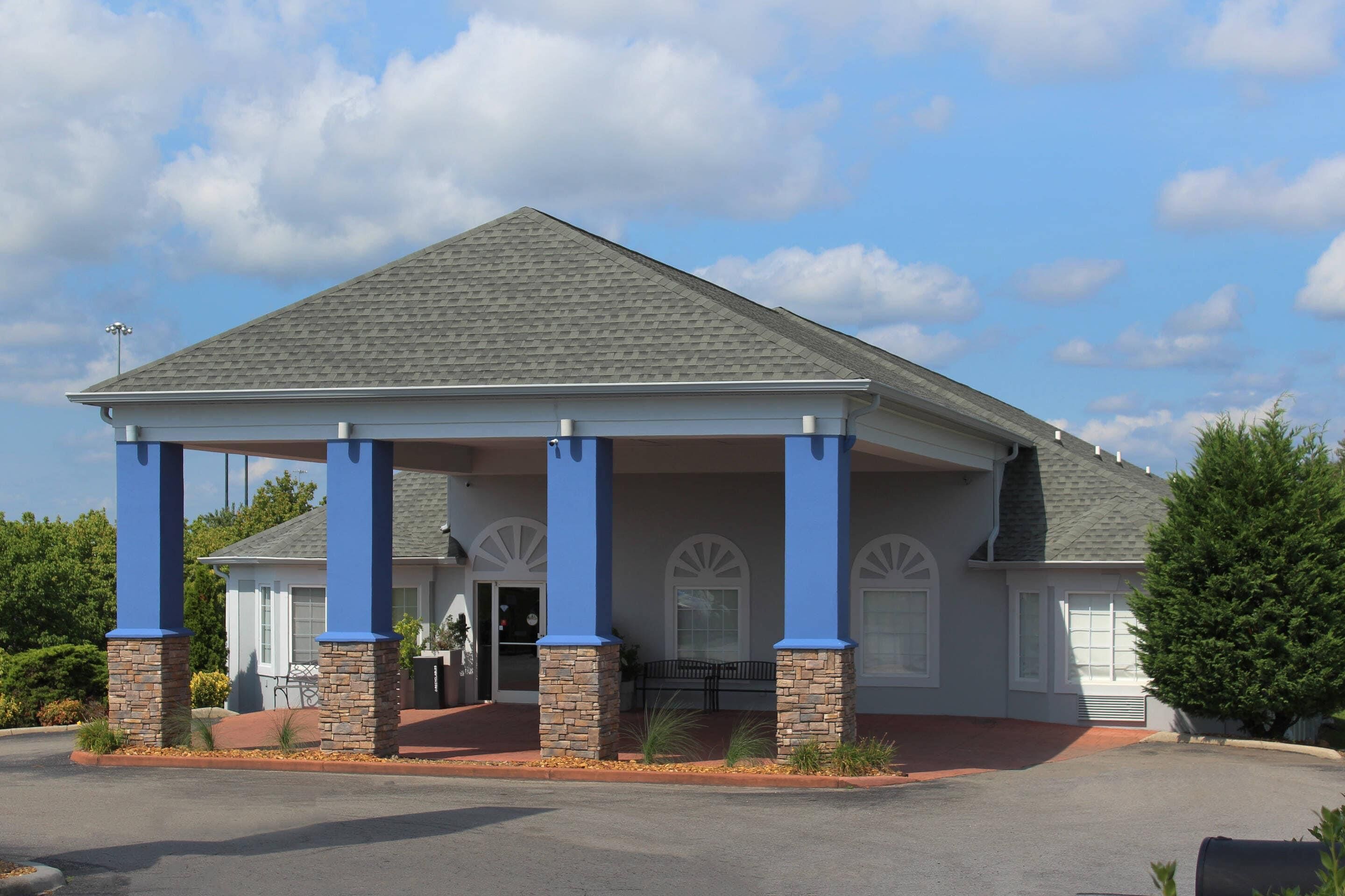 A building with a covered entrance, stone pillars, and a tiled roof.