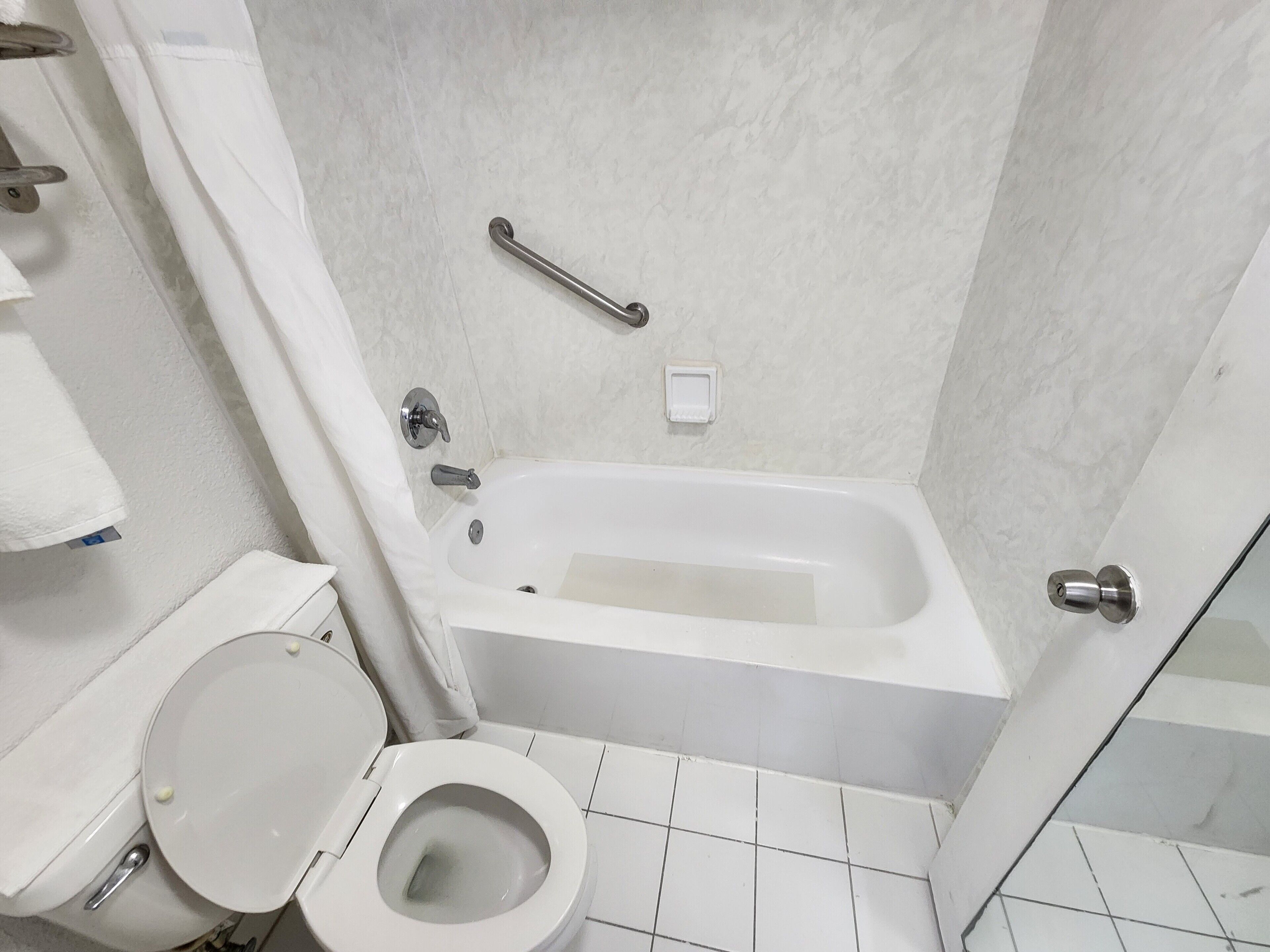 Un baño con una bañera blanca, un inodoro y una cortina de ducha.