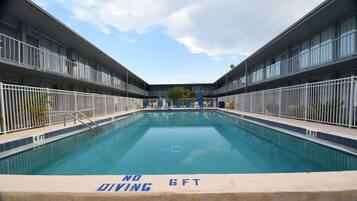 A swimming pool with a 'NO DIVING' sign, surrounded by a fence, and a '6 FT' depth marker.