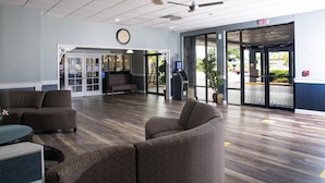 A lobby with seating, a reception desk, an ATM, and a clock on the wall.