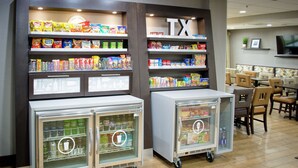 Un espace dédié à la présentation des collations et des boissons, comprenant des présentoirs réfrigérés et des étagères remplies de diverses collations et boissons.