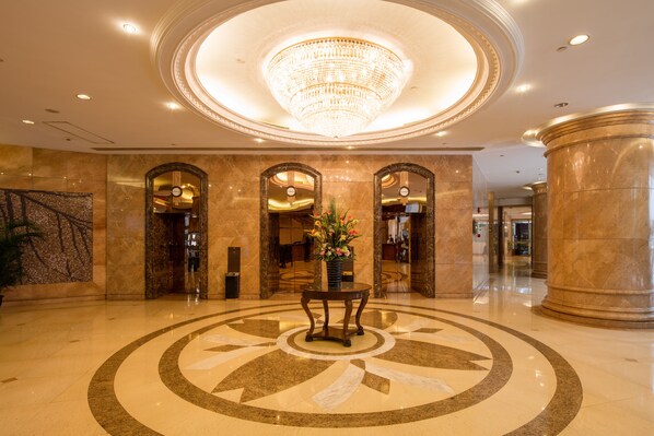 A lobby with a large circular marble floor, a central chandelier, and a potted plant. - City Hotel Shanghai (Shanghai)