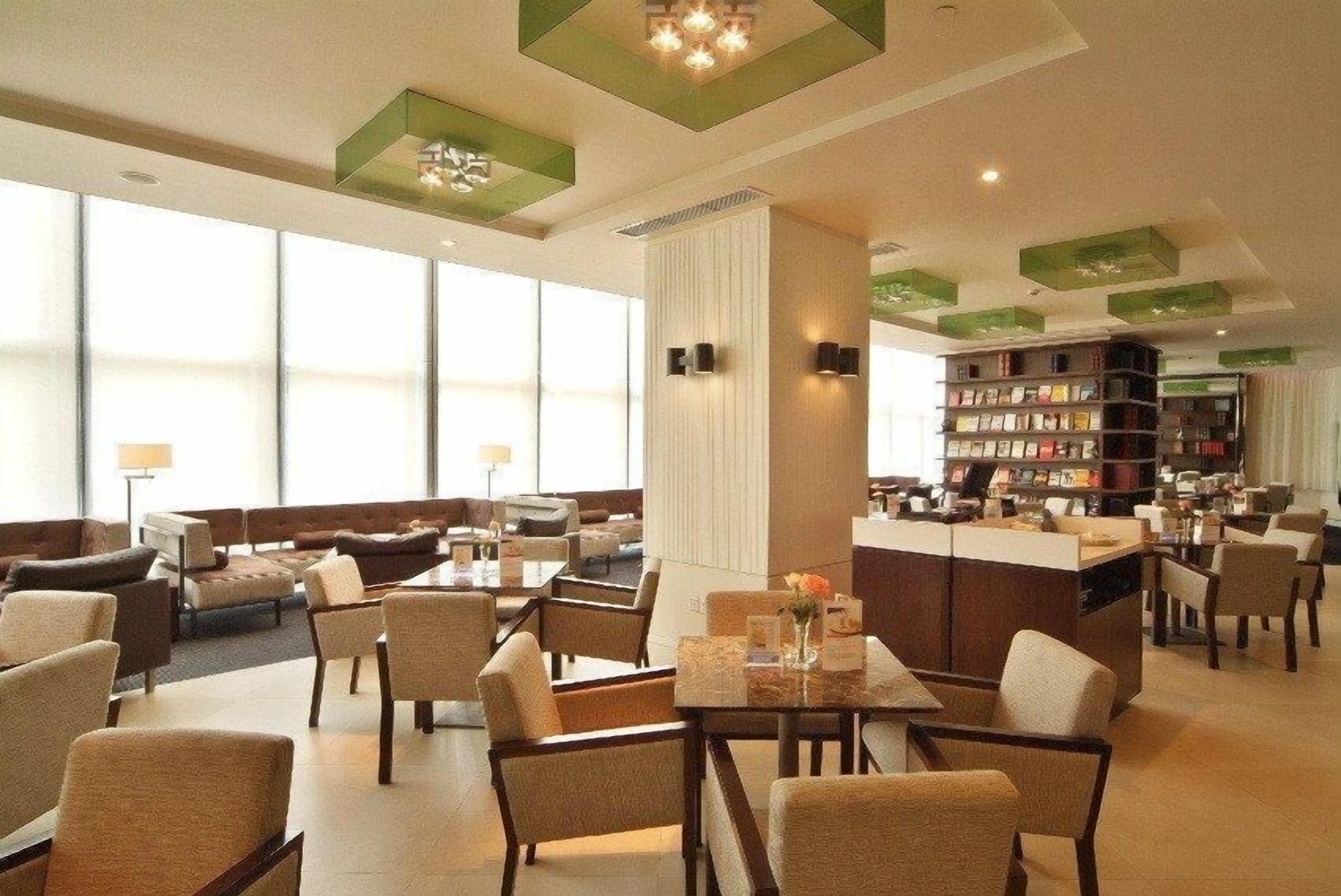 A hotel lobby with multiple seating areas, a reception desk, and a bookshelf.
